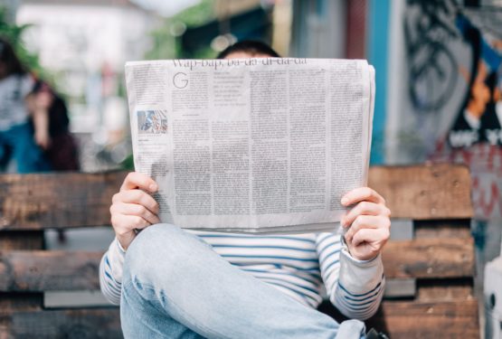 Man reading newspaper on wooden bench