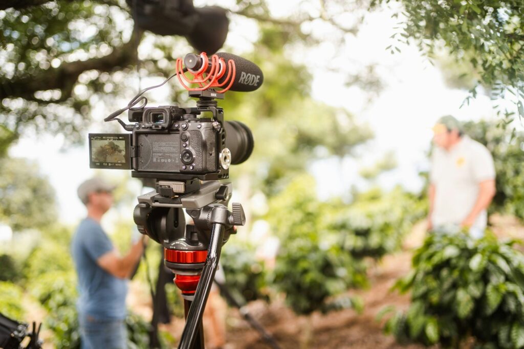 A camera and microphone on a tripod points toward a person being interviewed